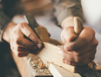 A pair of hands chiseling away at a wooden block