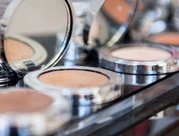 Makeup powders in silver compacts in a line on a shelf