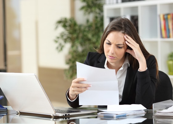 Business woman at a desk reading a tax bill, looking tense