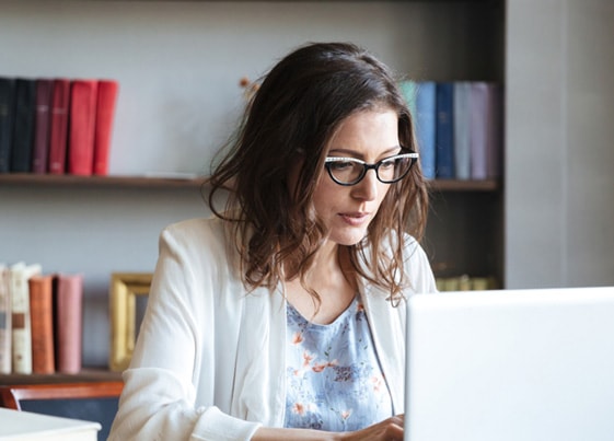 woman wearing glasses reading about tax write offs on a laptop